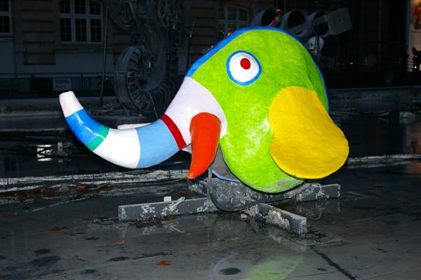 Colorful elephant-shaped sculpture on wet pavement at night