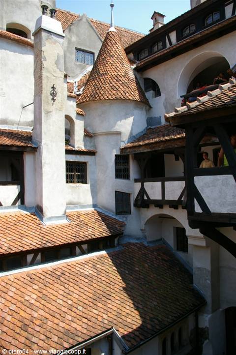 Inner courtyard of Bran Castle, conical shingled tower, wooden beams and visitors