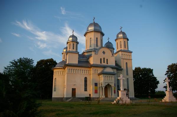 Orthodox church with silver domes and crosses, golden light on the lawn