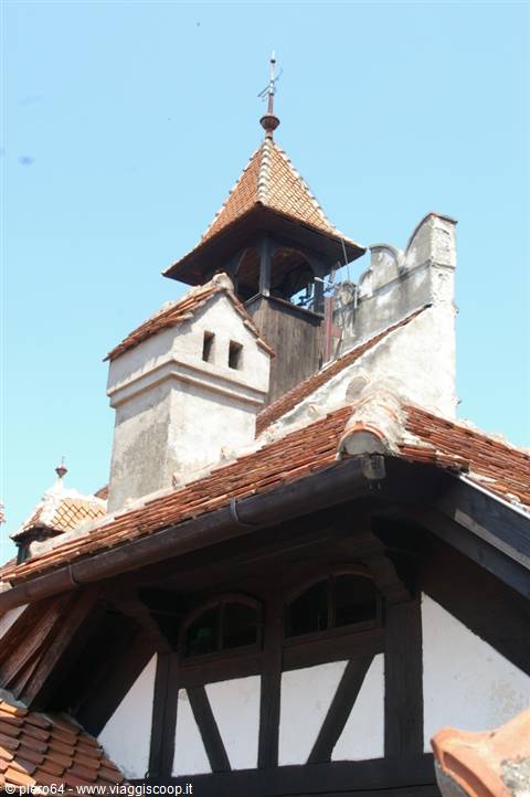 Red tile roofs and wooden turret of Bran Castle under the blue sky