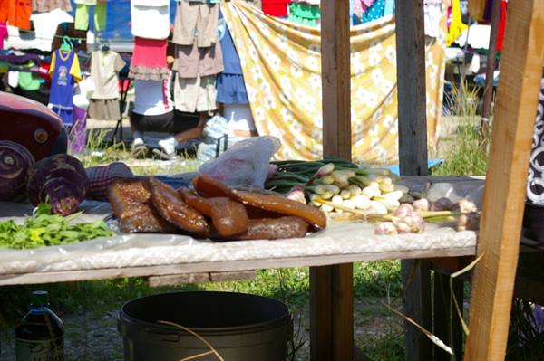 Outdoor stall with honeycomb, fresh garlic and vegetables, laundry hanging behind