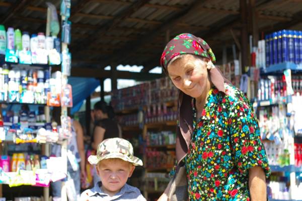 Woman in floral headscarf and boy in hat at a market kiosk