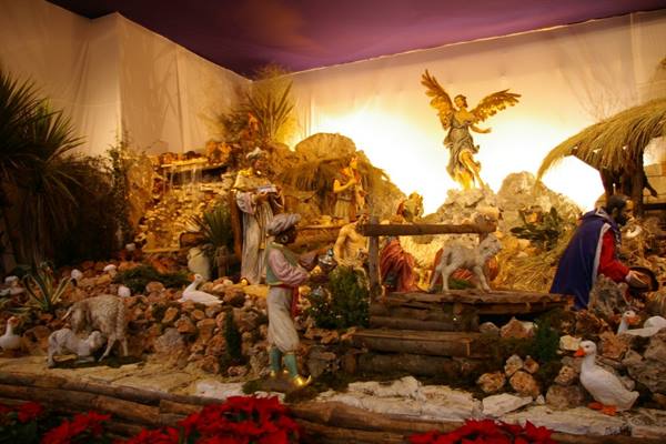 Nativity scene with figurines, shepherds, golden angel and warm lighting