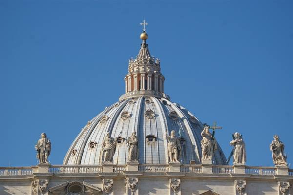 St. Peter's Basilica dome, saint statues along the balustrade, sunlight, blue sky