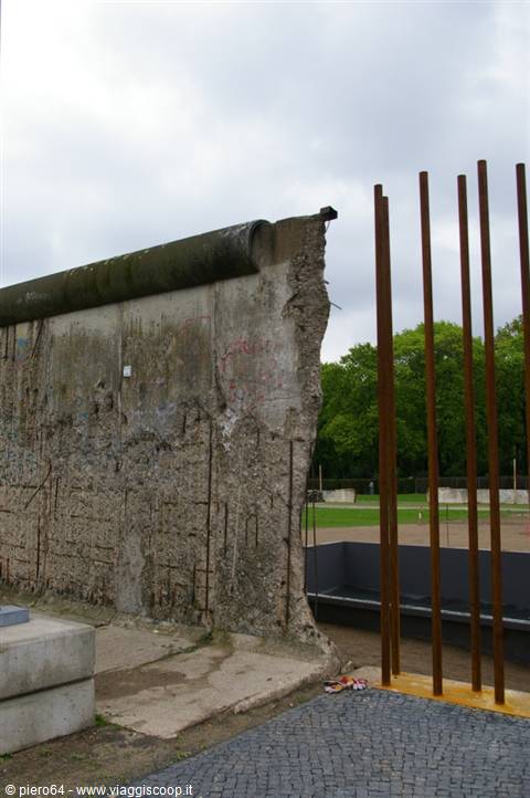 Concrete segment of the Berlin Wall with steel bars, overcast sky