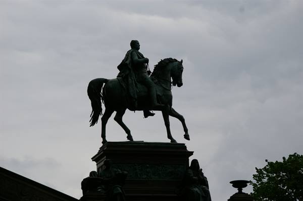 Equestrian bronze statue silhouetted against a cloudy sky