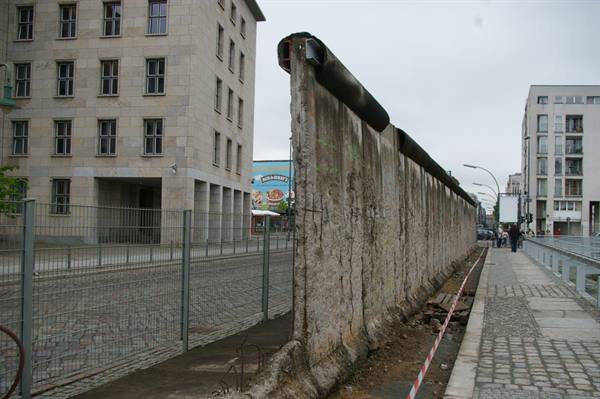 Concrete segment of the Berlin Wall along the street between stone buildings