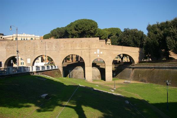 Brick walls with large arches above a green lawn, Rome