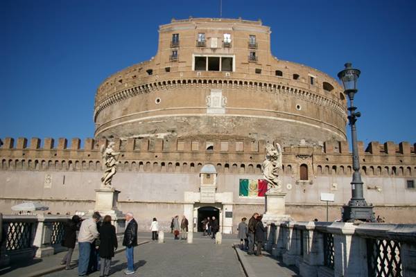 Tourists on bridge in front of Castel Sant'Angelo in Rome, blue sky, Italian flag