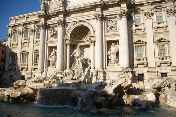 Trevi Fountain, baroque marble statues among cascades under bright sunlight