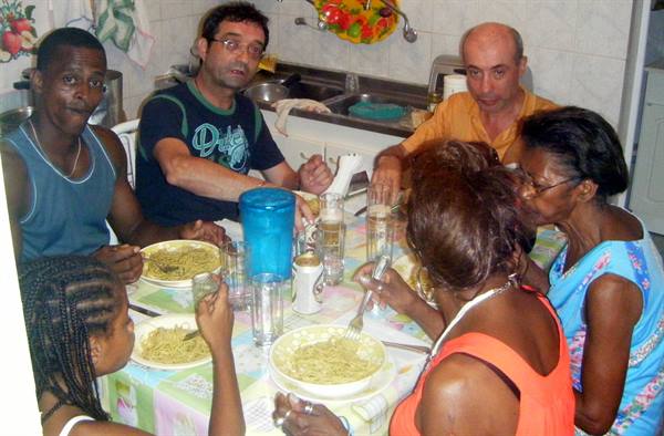 Friends and family eating spaghetti at kitchen table with colorful tablecloth