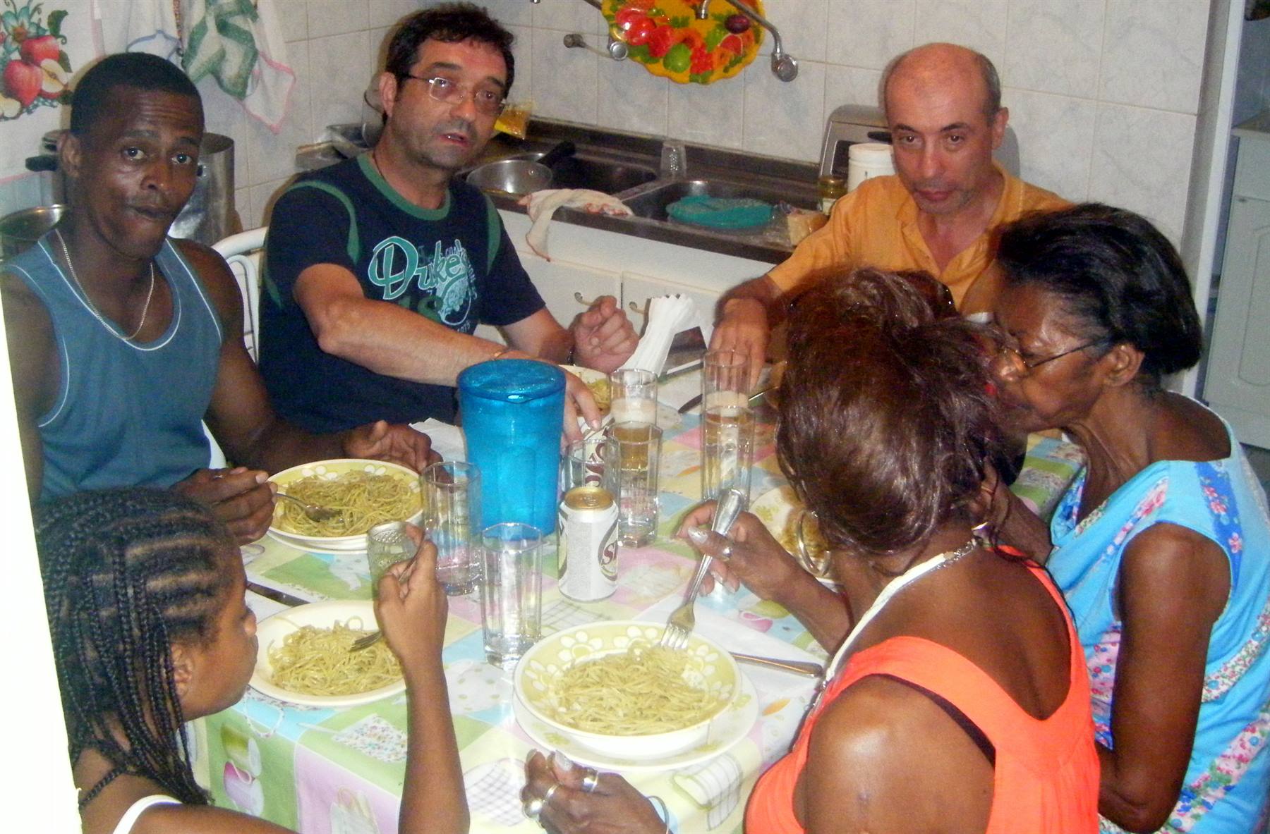 Friends and family eating spaghetti at kitchen table with colorful tablecloth