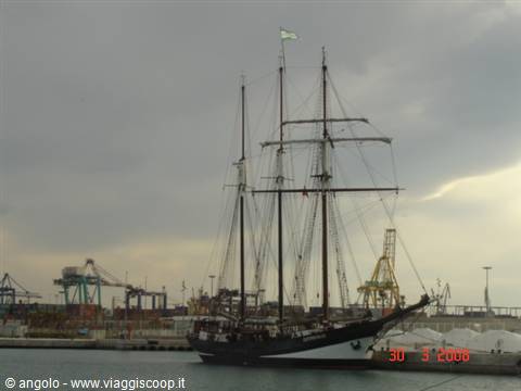 Three-masted tall ship moored at Barcelona harbor under cloudy sky