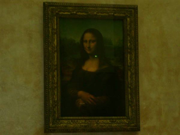 Leonardo's Mona Lisa framed, hanging on the yellow wall of the Louvre Museum