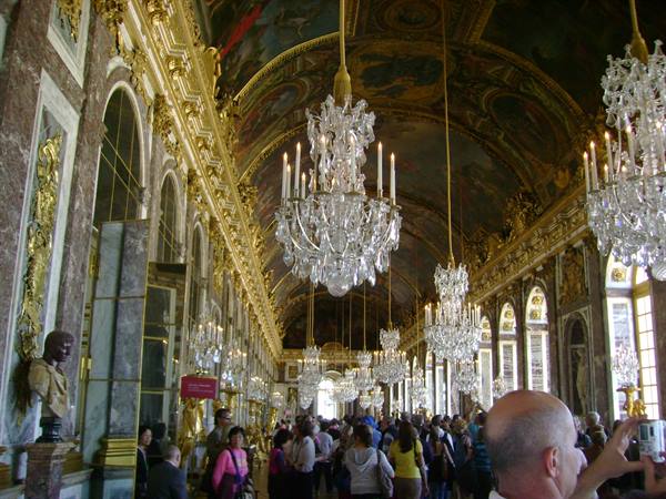 Hall of Mirrors at Versailles: tourists beneath crystal chandeliers and gilded decorations