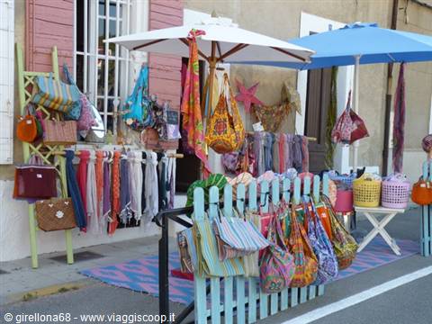 Market stall with colorful bags and clothes under parasols, blue fence
