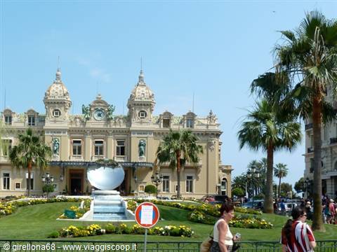Tourists strolling in front of the Monte Carlo Casino among palms and flowerbeds
