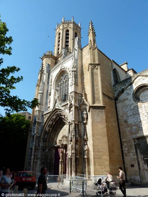 Gothic facade of Aix-en-Provence cathedral, carved statues, people under sunny sky