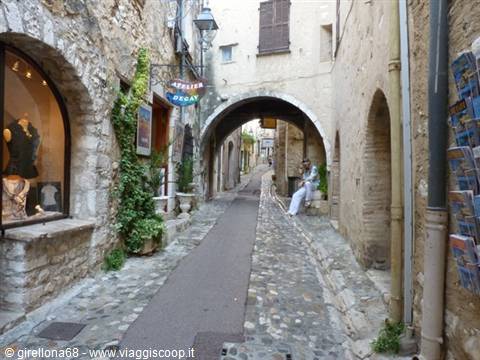Cobbled stone alley with arch in Saint-Paul-de-Vence, man sitting in shade