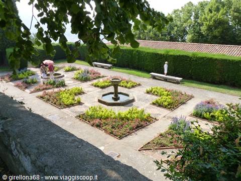 Formal garden with central stone fountain, geometric flowerbeds and green hedges