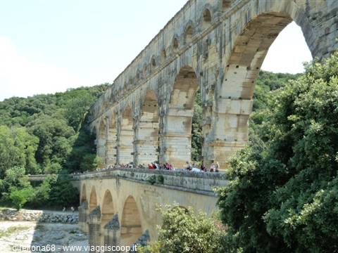 Tourists walk across the massive stone arches of Pont du Gard