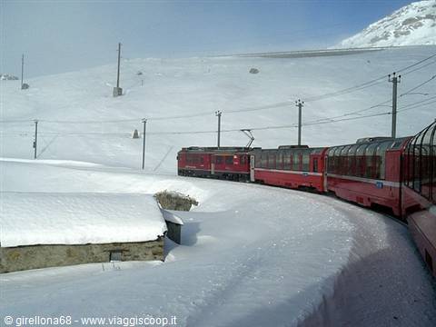 Red Bernina Express train winding through deep snow in the mountains