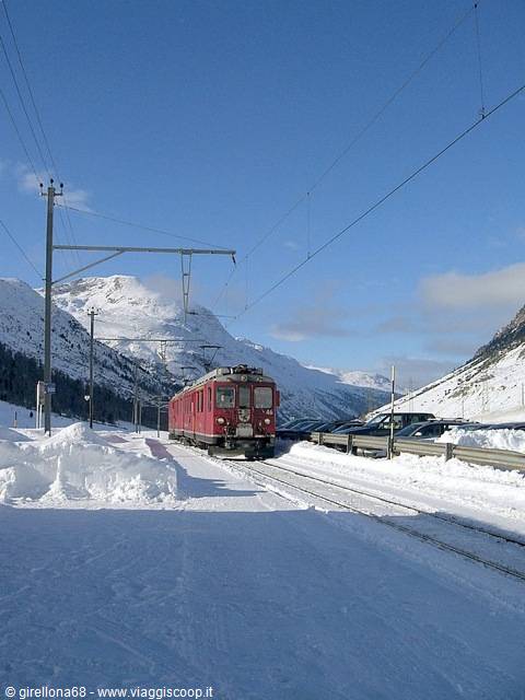 Red Bernina train stopped in the snow among snowy mountains