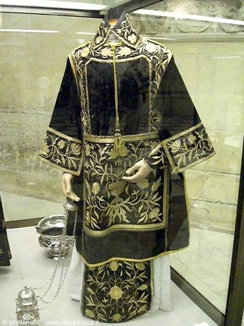 Black liturgical vestment with gold embroidery on mannequin, silver censer