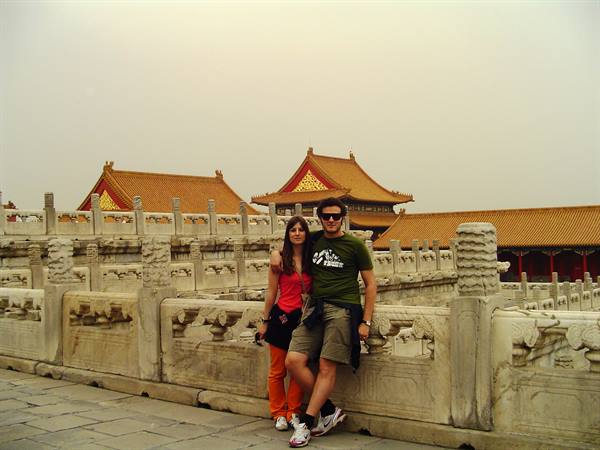 Couple leaning on a marble balustrade with golden roofs of the Forbidden City