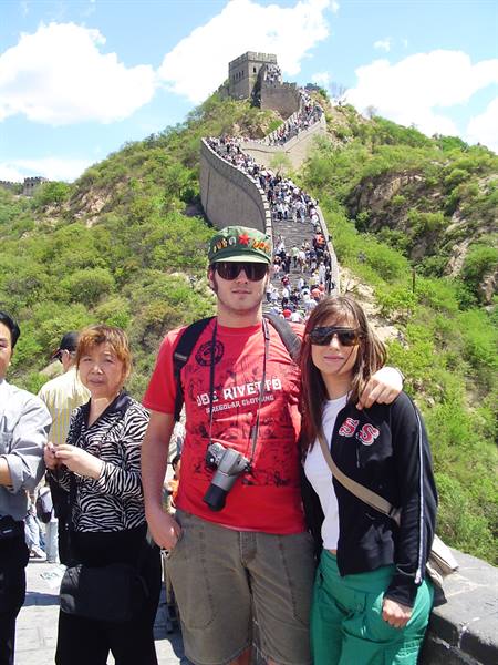 Tourists posing at the Great Wall of Badaling below a crowded tower