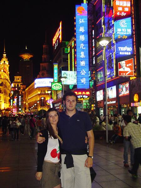 Tourist couple on Nanjing Road, Shanghai, among glowing neon signs at night