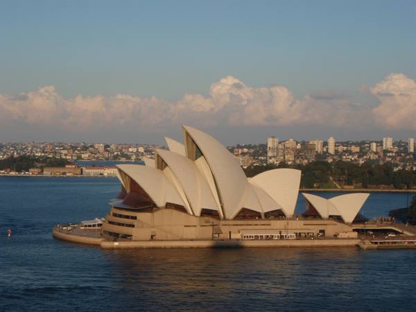 Sydney Opera House with white shells glowing across the harbour water