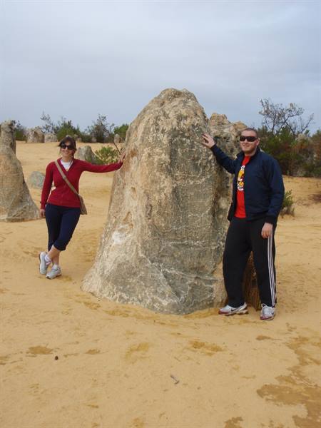 Couple beside a limestone pinnacle at the Pinnacles, yellow sand and grey sky