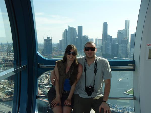 Couple with camera inside Singapore Flyer capsule, skyscrapers in the background