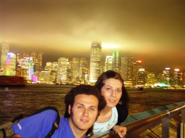 Couple leaning on railing in front of Hong Kong's illuminated skyscrapers