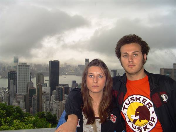 Couple in front of Hong Kong skyscrapers under clouds from Victoria Peak