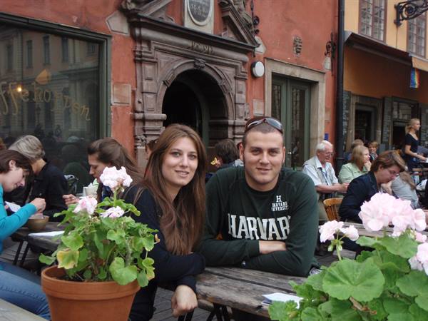 Smiling couple at outdoor café table with geraniums at Stortorget, Stockholm