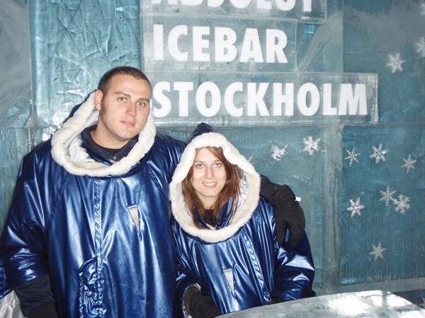 Couple in blue fur-lined capes inside Stockholm's Absolut Icebar, ice walls