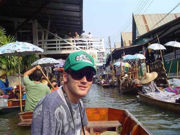 Tourist on a boat at a floating market, wooden boats and umbrellas along the canal