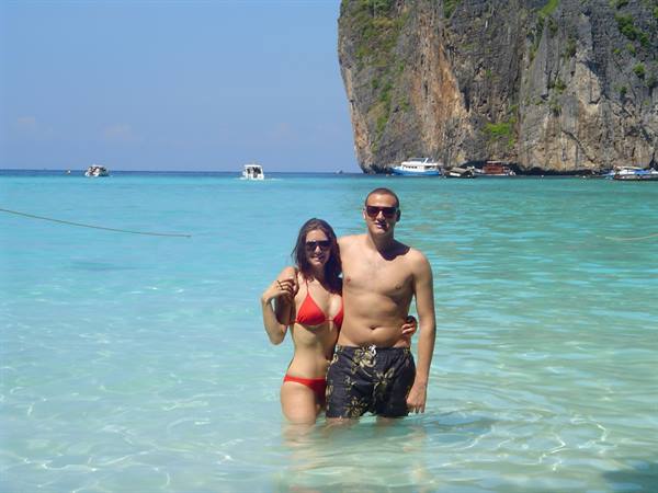 Couple in turquoise water at Maya Bay, Phi Phi, limestone cliffs and boats