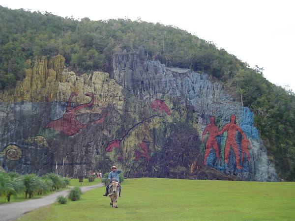 Horse rider in front of the Mural de la Prehistoria painted rock, Viñales
