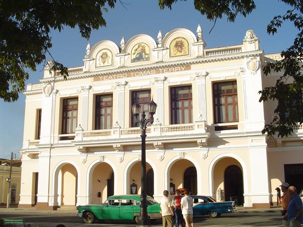 Teatro Tomás Terry in Cienfuegos, pale facade with arches, vintage cars under lamppost