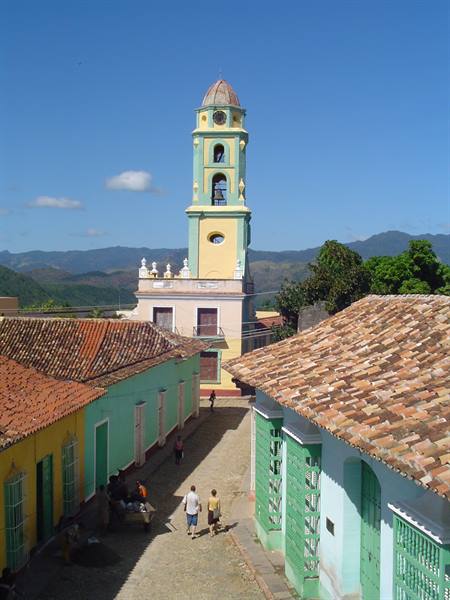 Yellow and green colonial bell tower above turquoise houses in Trinidad