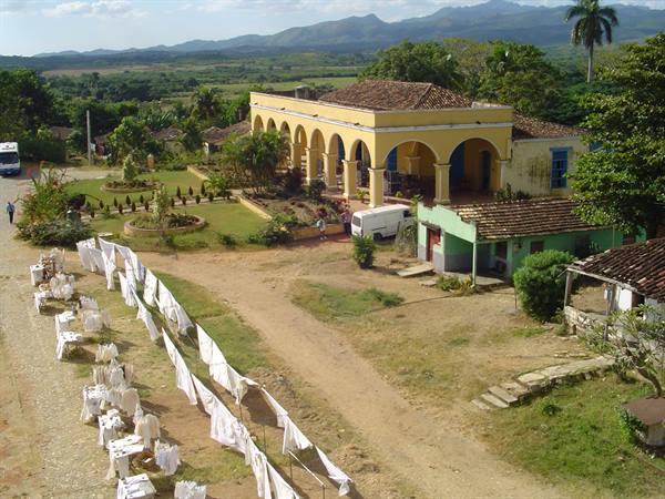 White tablecloths drying in front of yellow hacienda with arches among green hills