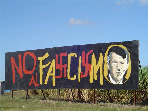 Painted anti-fascism billboard with Hitler's face among green cane fields