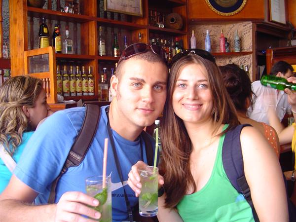 Couple with mojitos at a wooden bar counter in a busy pub