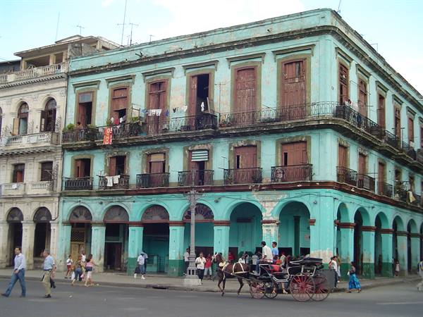 Horse-drawn carriage passing a weathered turquoise colonial building in Havana