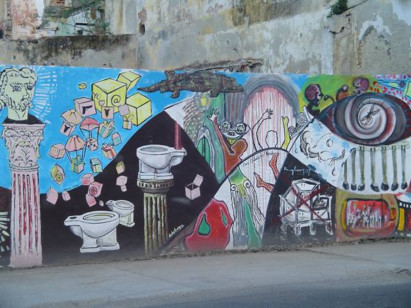 Colorful mural on crumbling wall featuring toilets, classical column and eye