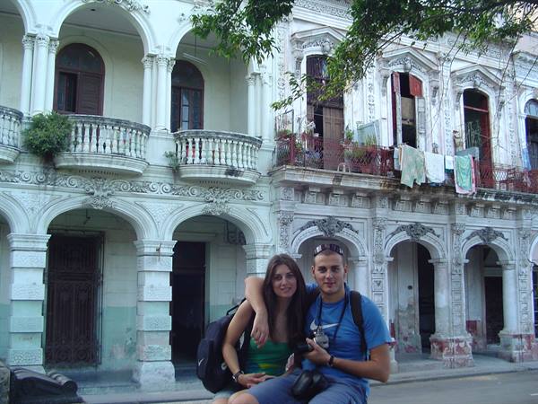 Smiling couple in front of an old colonnaded building, laundry on balconies