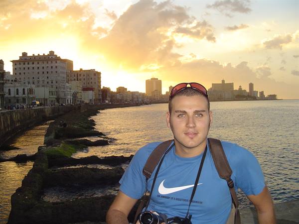 Tourist with camera on Havana's Malecón seawall at sunset
